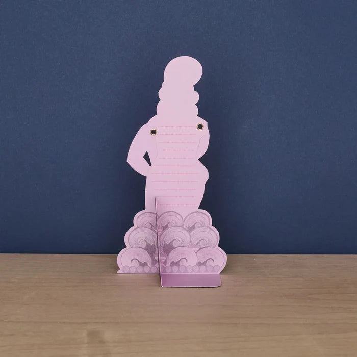 The back of a standing pink die-cut card shaped like a dancer, featuring dotted lines on her torso for writing a message and a fold-out base stand.