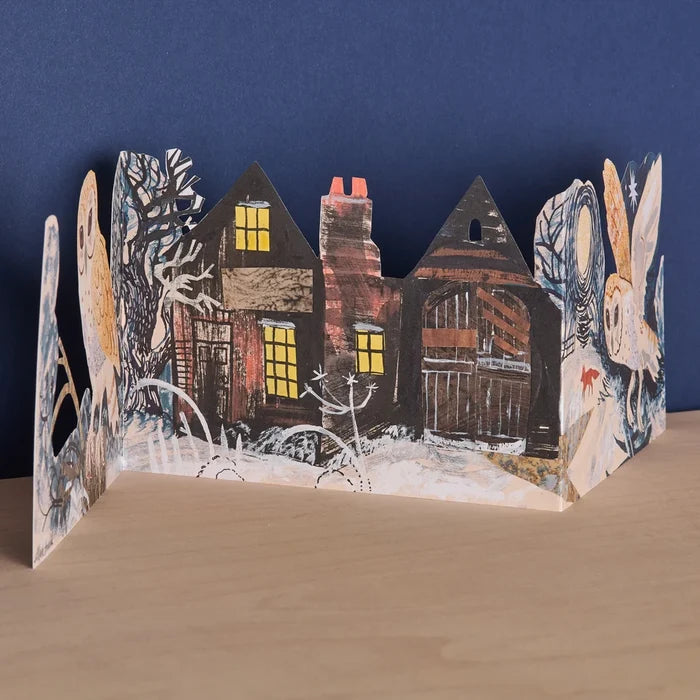 The front view of the freestanding three-panel die-cut card showcasing a snowy night landscape with glowing cottage windows, a red fox, and barn owls in flight.