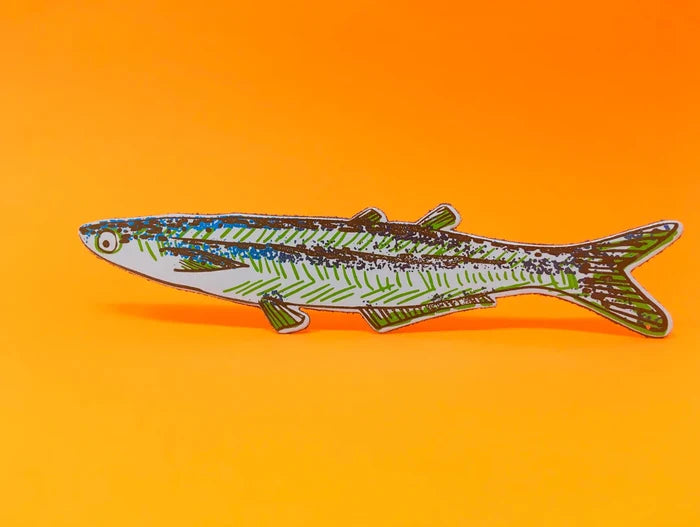 A fish-shaped bookmark with a light blue base, green striped pattern, and multicolored glitter details, displayed against a solid orange background.
