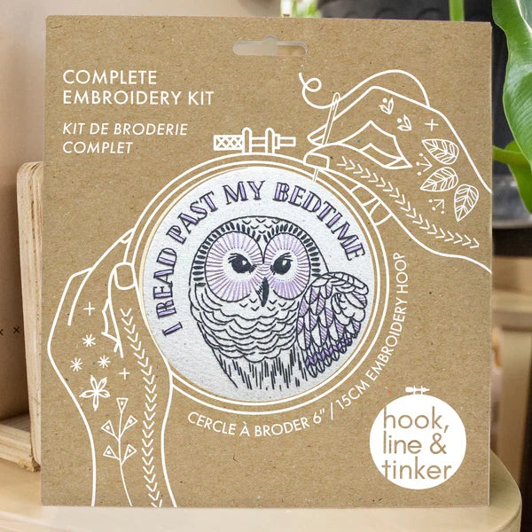 Embroidery kit packaging with owl design and branding on a neutral background