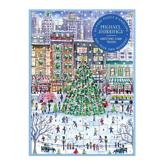 A square jigsaw puzzle notecard cover featuring a colorful winter city scene with a large decorated Christmas tree, skaters in an ice rink, buildings, and people. A blue circular badge at the top right reads 'Michael Storring's Greeting Card Puzzle'.