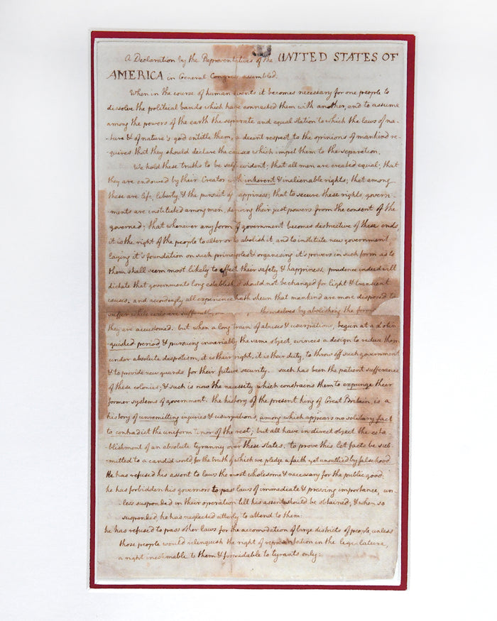 A full, top-down view of a historical replica print of Thomas Jefferson's handwritten draft of the Declaration of Independence, showing the complete text on faded, tea-stained paper with a thin red border.