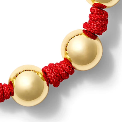 Bracelet with gold and textured red threads on a white background