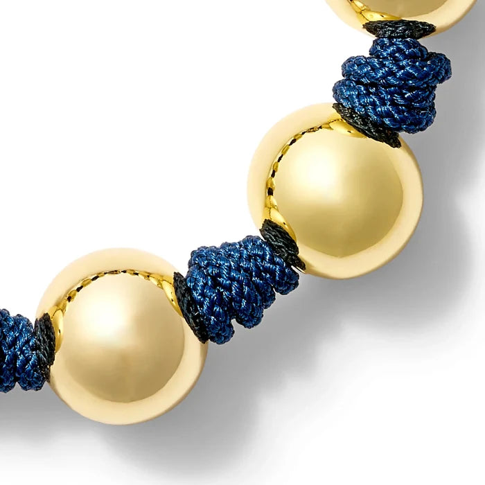 Bracelet with gold and textured navy blue threads on a white background