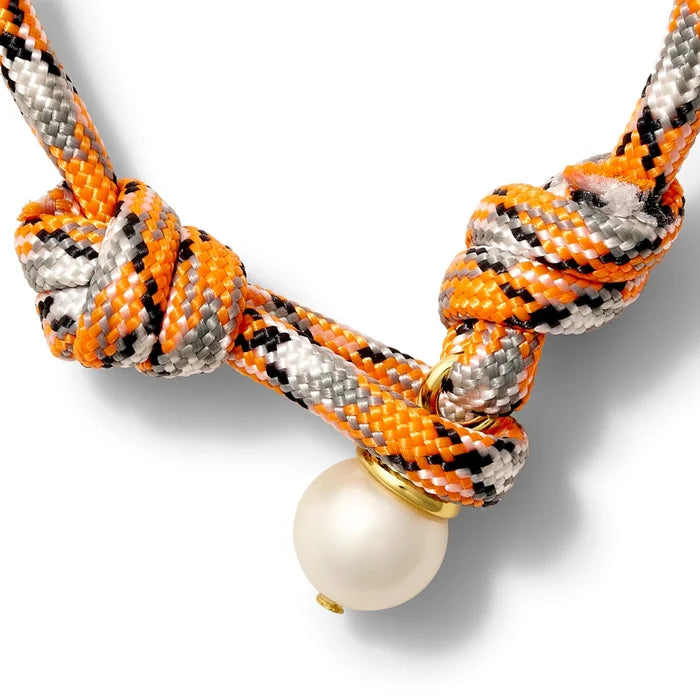 Orange, white, and black bracelet with a pearl button closure on a white background