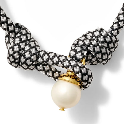 White and black bracelet with a pearl button closure on a white background
