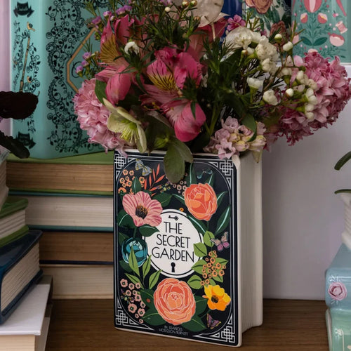 A decorative book-shaped vase with a floral illustration simulating 'THE SECRET GARDEN' book.